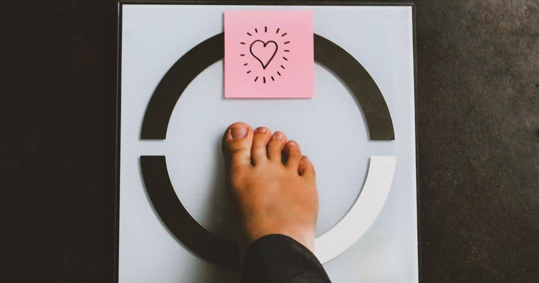 Fuß auf Waage mit Herzsymbol bei Gewichtsabnahme-Ziel