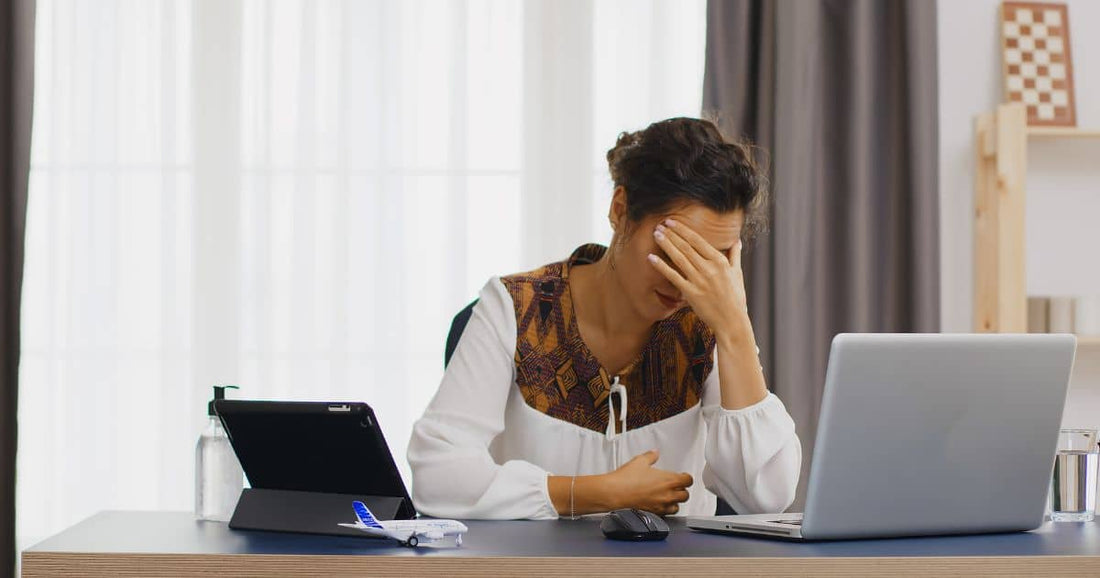 Gestresste Frau am Schreibtisch stützt Kopf mit der Hand.